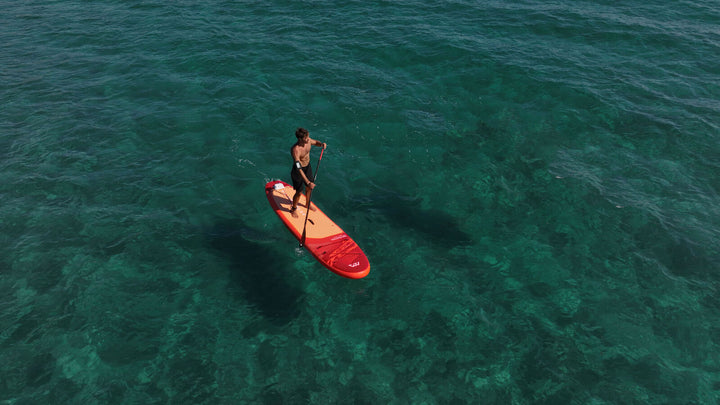 Aerial view of a paddler on the Aqua Marina Monster SUP over clear green water