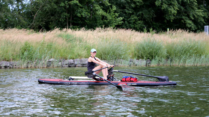 Rower sculling a ROWonAIR LITE 15 inflatable rowing board on flat water